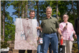 3 People Holding Image of Large Tree
