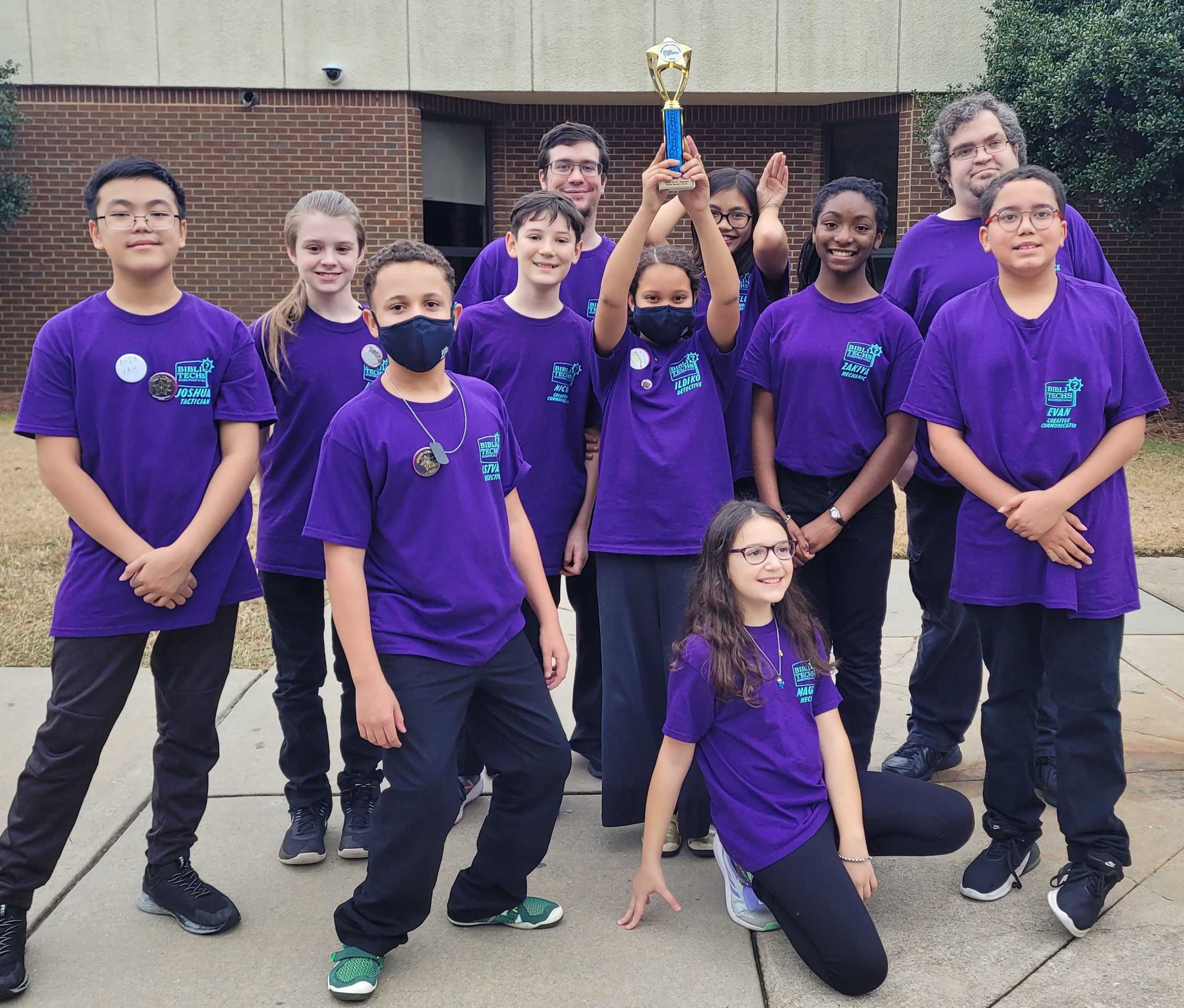 Photo of 9 Students Holding Up a Trophy