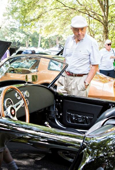 Man Looking at a Dark Convertible Car
