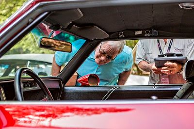 Man Peering Into a Red Sports Car