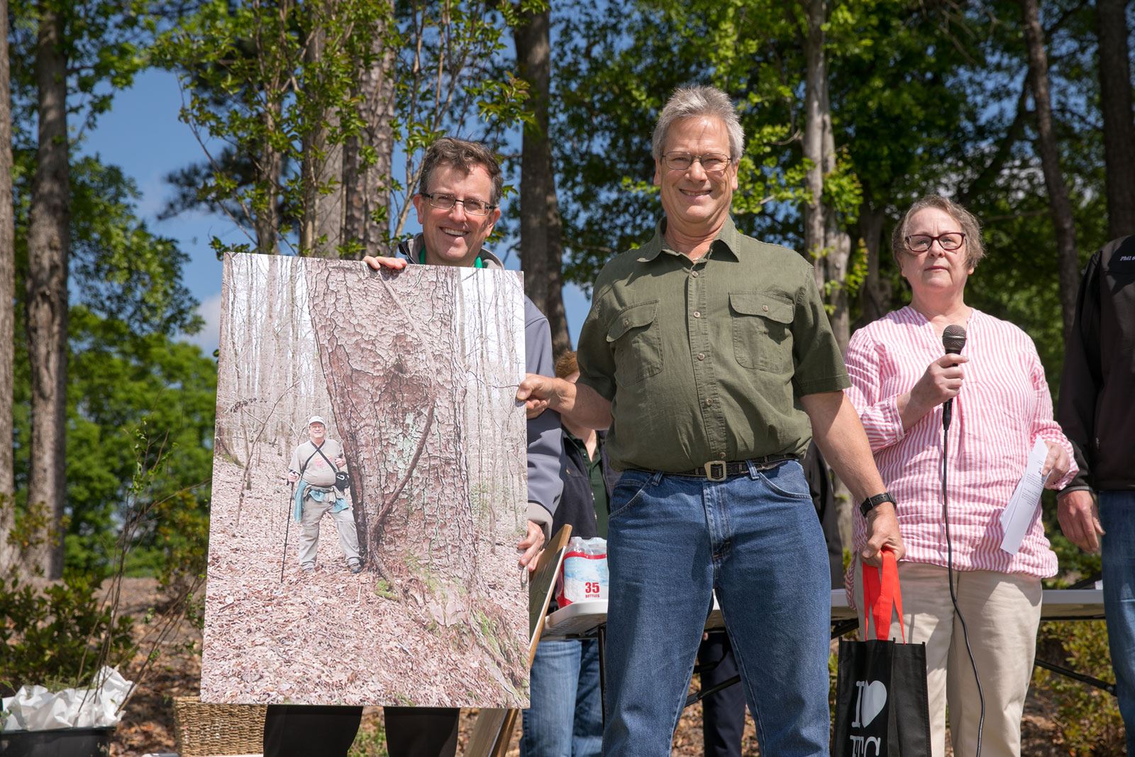 3 People Holding Image of Large Tree