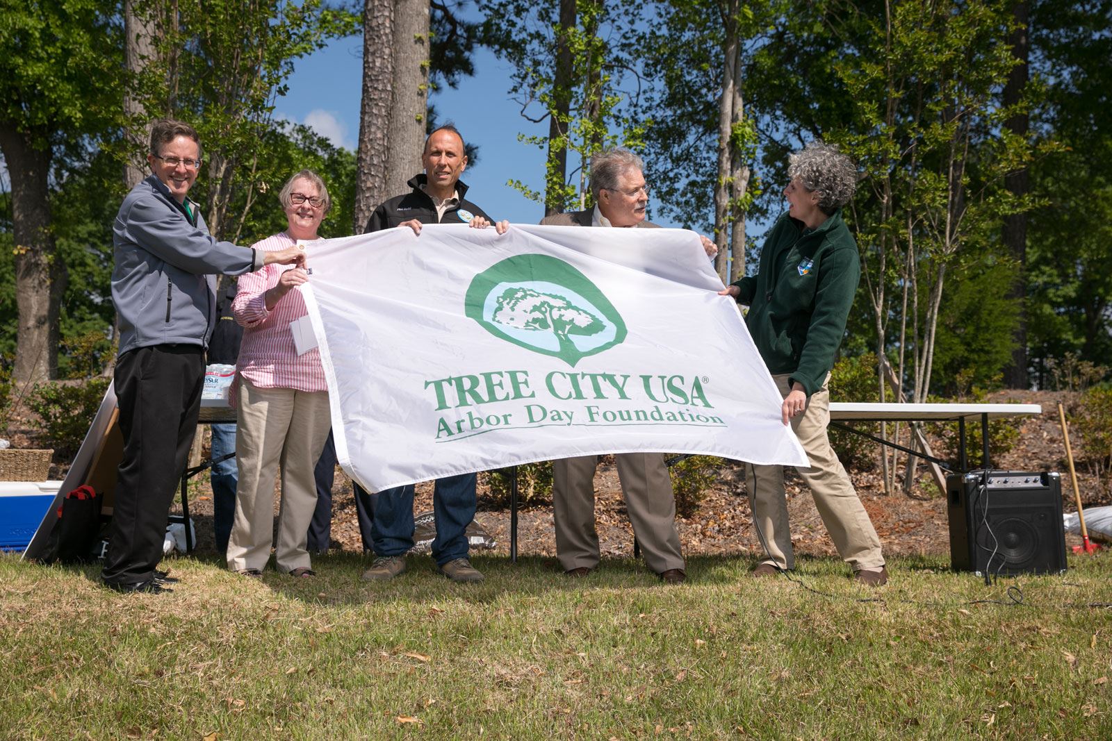 5 People Holding Tree City USA Flag